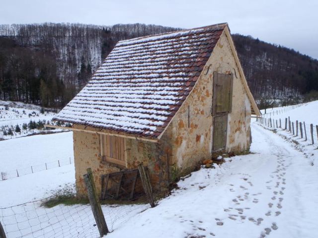 Restaurierte Feldscheune aus Bruchstein mit neuem Ziegeldach in verschneiter Landschaft